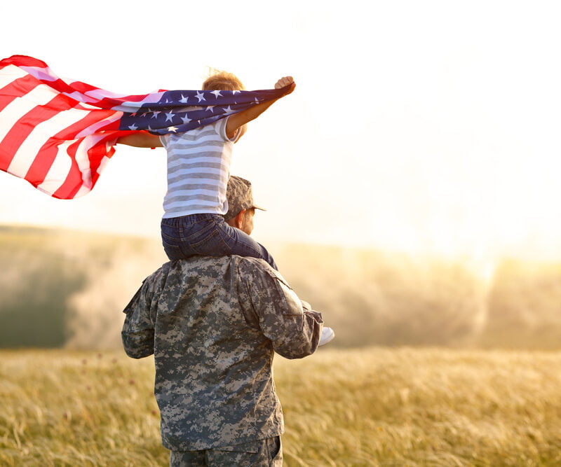 A father and son tandem while the carrying the flag of the United States of America - Chiropractic Care for Veterans